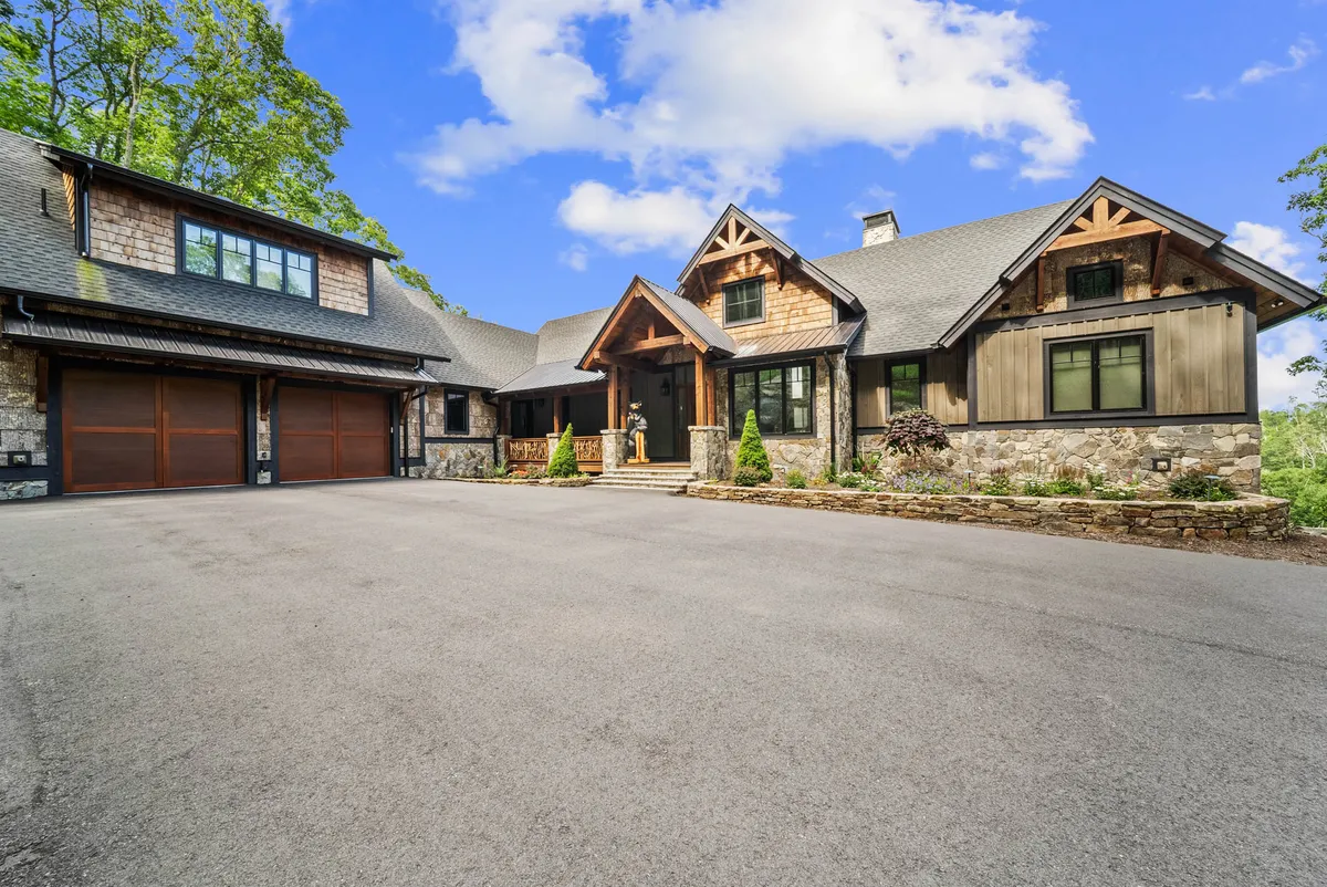 The grand main entrance features a large wooden door set in a stone façade, framed by a landscaped garden. The architecture exudes warmth and offers a welcoming impression, perfect for greeting retreat guests or arriving at a memorable event destination.