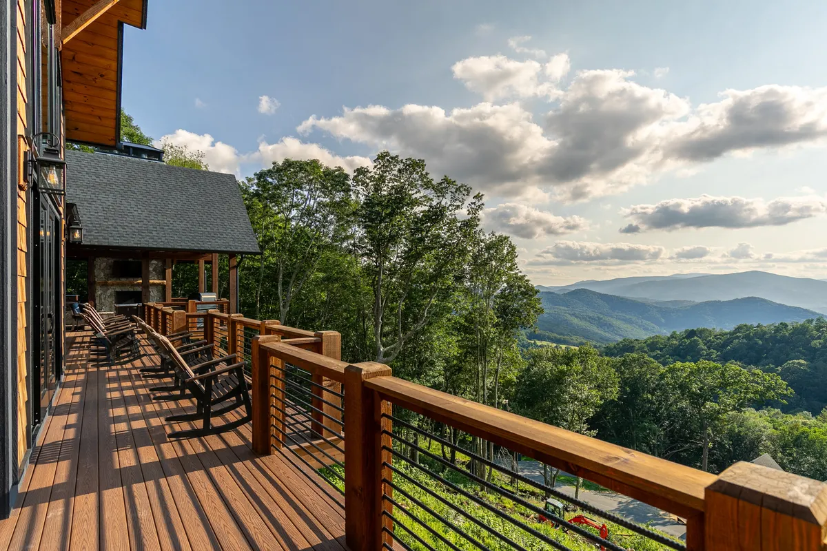 A serene deck with classic rocking chairs facing spectacular mountain views and dramatic skies. The setup suggests quiet moments, morning coffee, or stargazing, offering guests a tranquil connection to the surroundings.