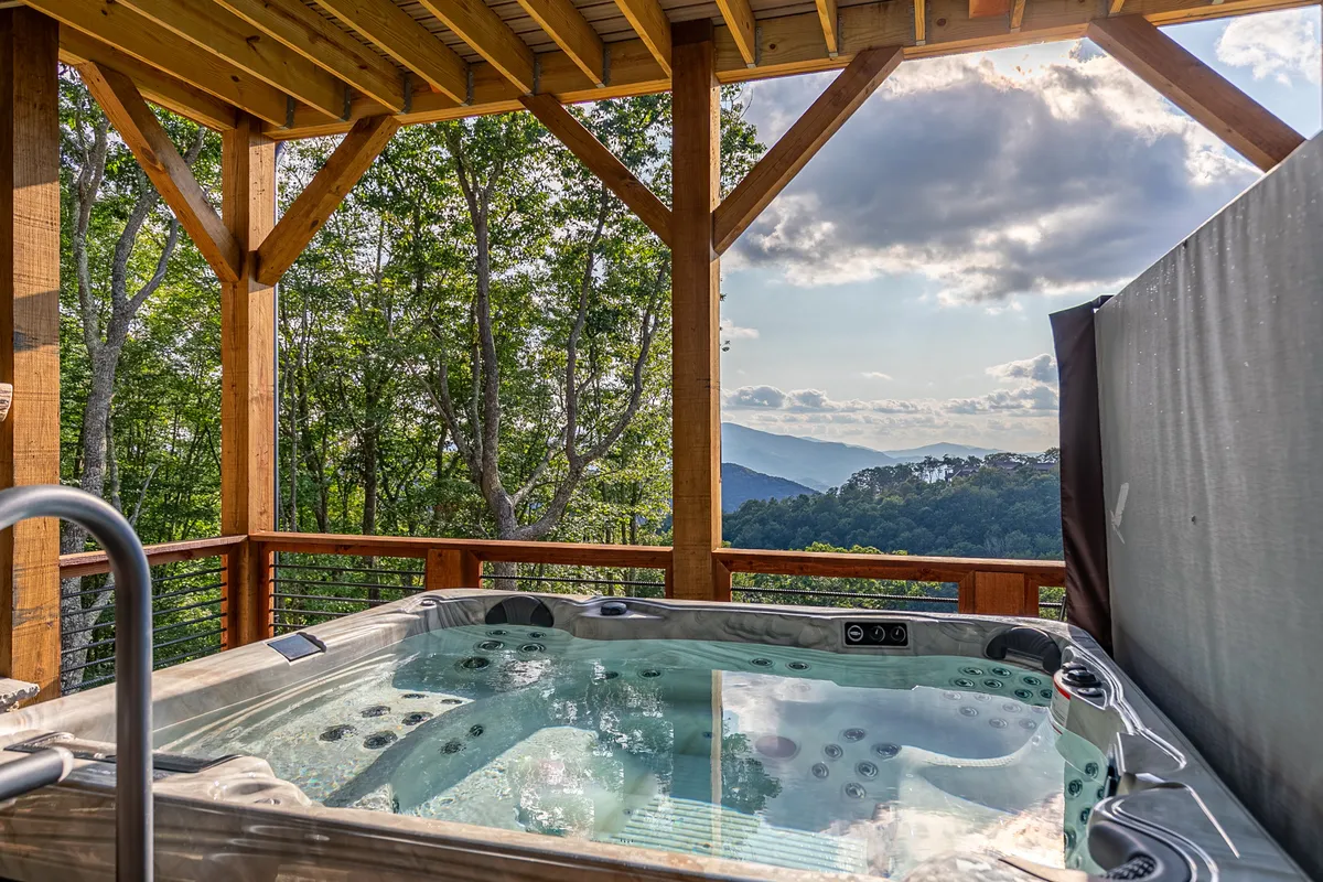 An inviting hot tub on a wooden deck, framed by sturdy timber beams and overlooking majestic mountain views. The space hints at moments of relaxation, socializing, and stargazing after a day spent exploring the outdoors.